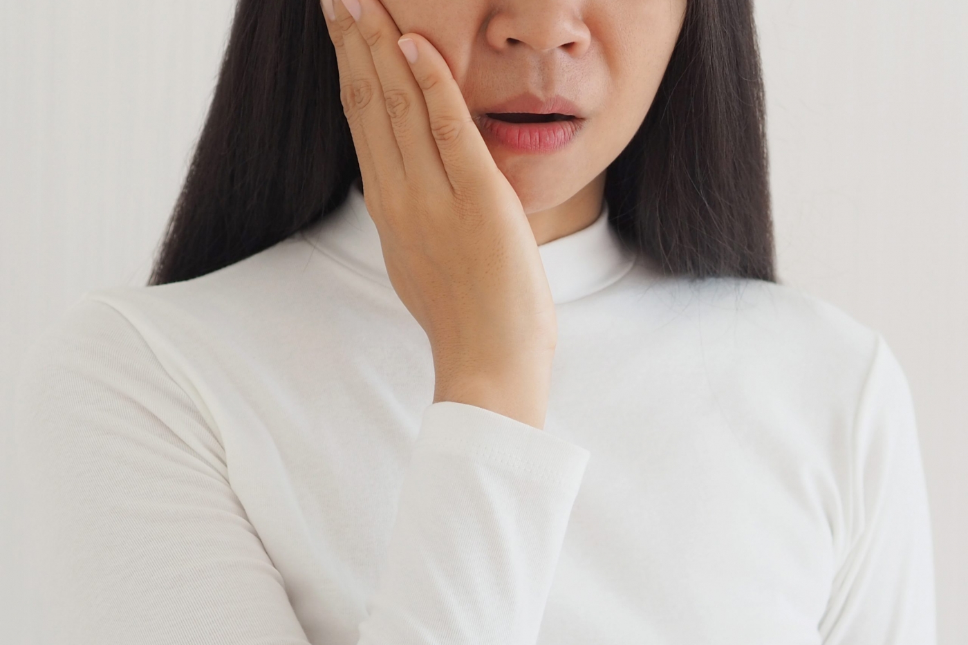 trigeminal neuralgia and temporomandibular joint and muscle disorder in asian woman, She uses hand touching her cheek and symptoms fo pain and suffering on isolated white background.