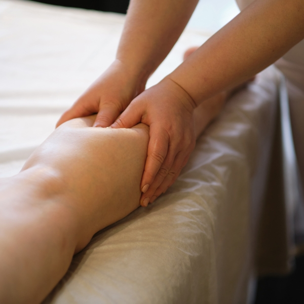 Detail of hands massaging human calf muscle.Therapist applying pressure on female leg. Hands of massage therapist massaging legs of young woman in spa salon. Body care in spa salon for young woman
